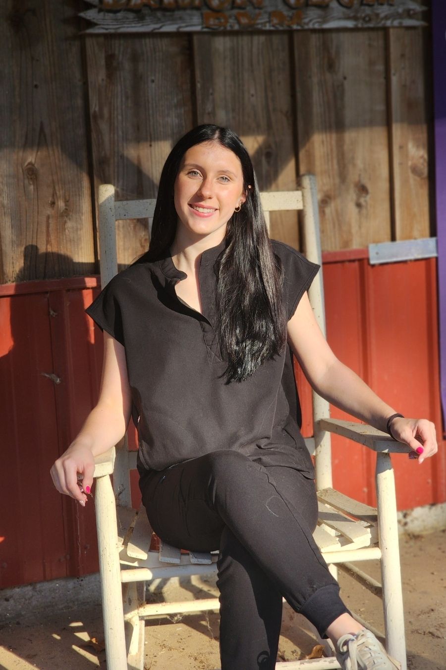 Kinman (1) Kinman sitting in a chair wearing black scrubs